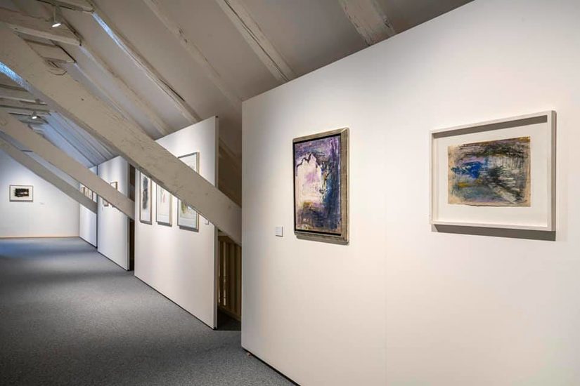 Ausstellungsansicht der zweiten Etage bunte Gemälden in unterschiedlichen Größen an weißen Stellwänden.