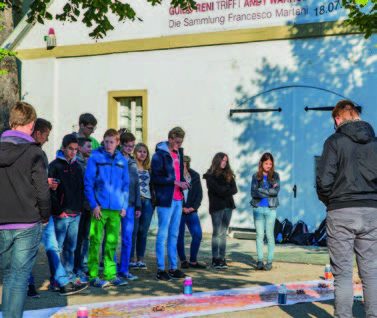 Ein Gruppe Jugendlicher vor der Galerie, auf dem Boden liegt eine Papierbahn mit verteilter Farbe.