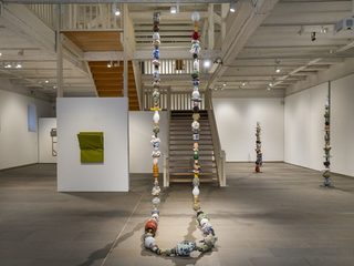 Ausstellungsansicht aus "Erweiterung der Möglichkeiten", die untere Etage Galerie in der Reithalle. Zentral vor der Treppe hängt eine Kette aus Keramikobjekten.