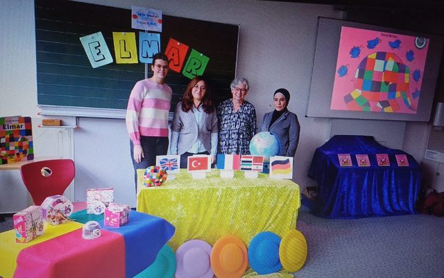 Die Vorleser stehen vor einem mit Flaggen geschmückten Tisch.