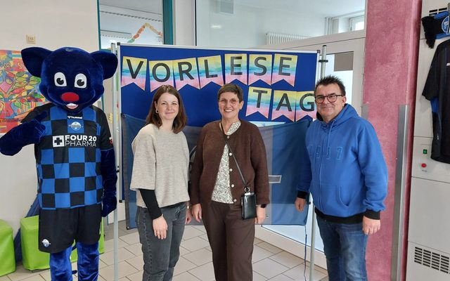 Frau Schäfers, Frau Haake, das Maskottchen und Herr Hornberger vor der Stellwand des Vorlesetages.