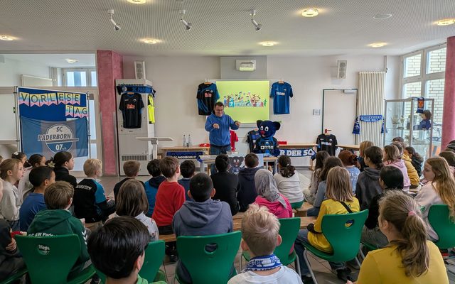 Kinder sind von hinten zu erkennen, Herr Hornberger und das Maskottchen Holy im Vordergrund.