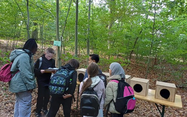 Die Kinder sind vor den Kühlboxen und lesen die Aufgabe.