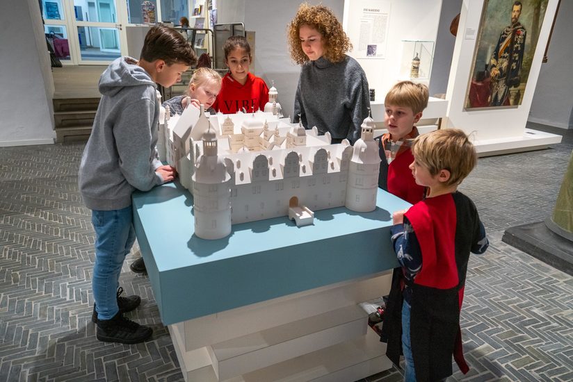 Fünf weiße Kinder die um das 3-D Modell des Schlosses Neuhaus stehen.