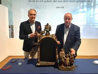Zwei Männer stehen vor Kunstwerken im Diözesanmuseum bzw. halten diese in der Hand
