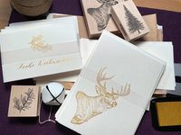 Es sind verschiedene Karten zu sehen auf denen mit Kalligraphie gezeichnet wurde. Unter anderem ein Hirsch oder ein Weihnachtsbaum in Gold
