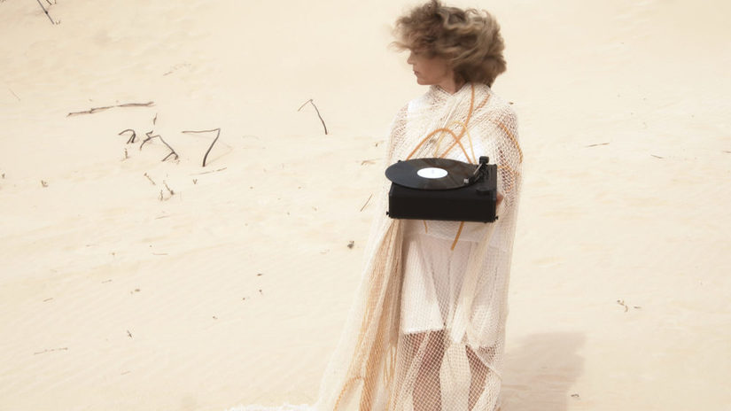 Frau mit weißem Gewand steht in der Sandwüste