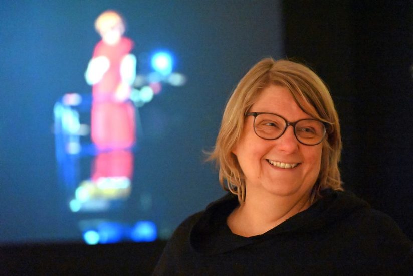 Die Kuratorin Christiane Ruhmann vor einem blauem Hintergrund